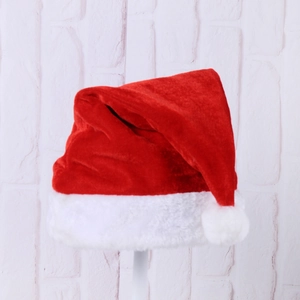 Close-up of classic red velvet Christmas hat with soft white plush trim and pom-pom detail