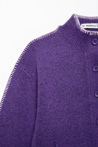 Dettaglio ravvicinato di cardigan viola in maglia con collo alto e cuciture a contrasto