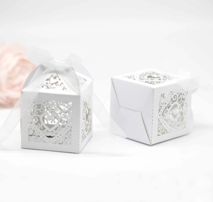 Detail of laser-cut white favor boxes with heart patterns and elegant white ribbons