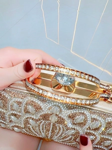 Close-up of gold rhinestone evening clutch bag with pearl details and diamond clasp