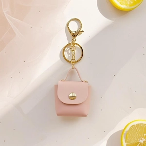 Close-up of a mini pink leather bag keychain with gold hardware on a white background