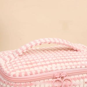 Close-up of plush checkered makeup bag featuring reinforced handle and dual zipper closure