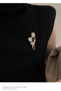 Close-up of luxury tulip brooch with white cubic zirconia and pearls on black vest