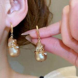 Détail macro des boucles d'oreilles nœud plaqué or 18k avec perle baroque et cristaux
