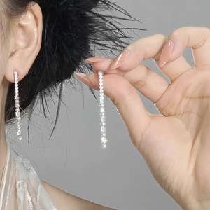Detailed view of long tassel earrings featuring sparkling zircon crystals and elegant pearls