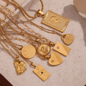 Flat lay of vintage 18K gold plated necklaces with diverse pendants on beige fabric