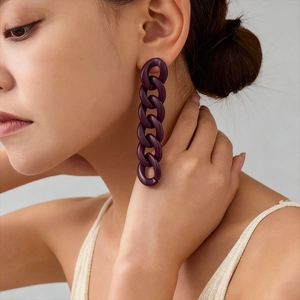 Close-up of purple acrylic chain link earrings worn by a model in soft lighting