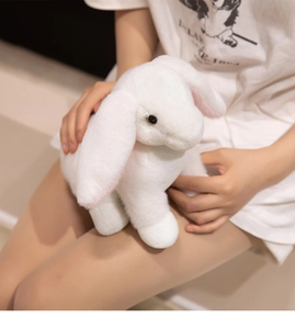 Close-up of a soft white plush lop-eared rabbit toy being held to show texture