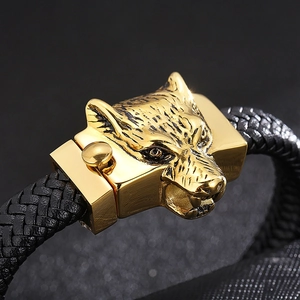 Macro shot of detailed golden wolf head clasp on a black braided leather bracelet for men