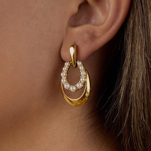 Close-up of golden double hoop pearl earrings showing glossy finish and elegant texture