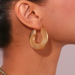 Detailed close-up of 18K gold-plated hoop earring with radial geometric texture on model
