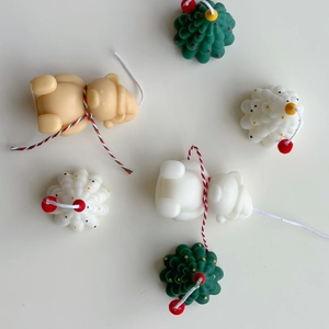 Detailed overhead view of mini Christmas tree and bear candles with festive ribbons