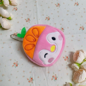 Detailed top view of a pink plush penguin coin purse with orange embroidery and keychain
