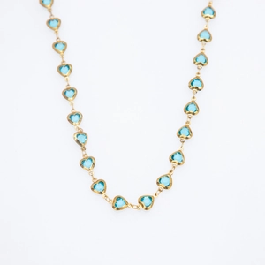 Detailed view of gold chain necklace featuring multiple blue heart-shaped glass charms