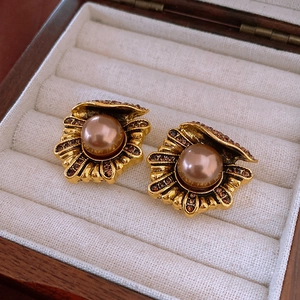 Close-up of vintage gold shell earrings with bronze pearls and crystals in a box