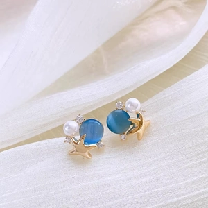 Dettaglio macro di orecchini a stella marina con opale blu, accenti di perle e zirconi cubici