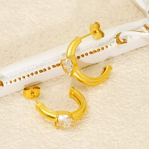 Detailed close-up of 18k gold heart-shaped zircon earrings on a vintage white frame