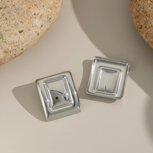 Macro shot of silver square stainless steel earrings with geometric relief on a stone