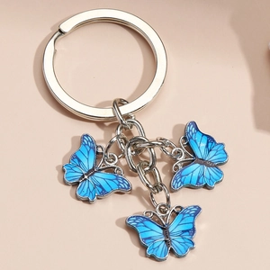 Metal keychain with three blue enamel butterfly pendants on a soft pink background