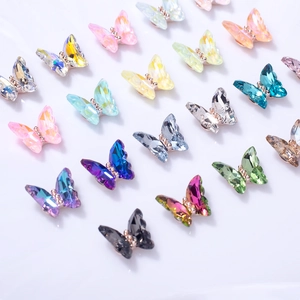 Detailed view of colorful crystal butterfly nail charms with gold-plated metal base