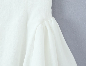 Detailansicht des weißen rückenfreien Kleides mit plissierter Chiffon-Textur und Raffungen