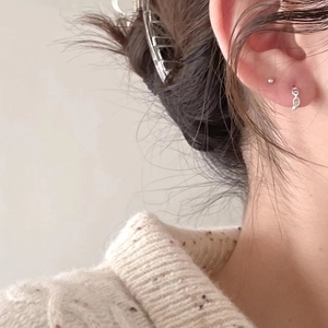 Detailed close-up of 925 silver stud and chain earrings worn with a chic metal hair claw