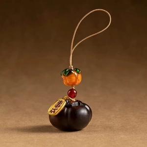 Detailed view of ebony persimmon charm with amber glass bead and golden metal tag