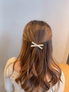 Detail of cream white pearl hair clip with crisscross design worn on a model hair