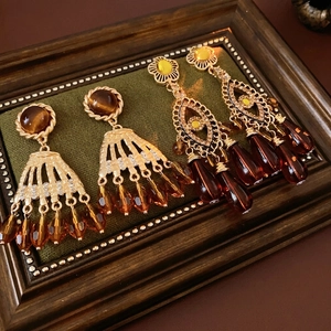 Vintage gold tassel earrings with tiger eye stone and crystal accents on green velvet