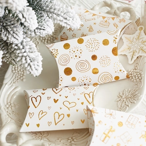 Pillow gift boxes with gold foil patterns on white paper in a decorative tray