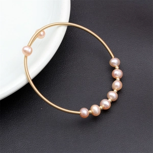 Detail of pink freshwater pearls and gold beads on a woven minimalist wire bracelet