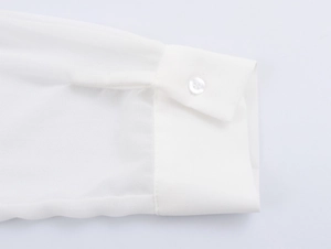 Détail du poignet d'une chemise en satin blanc avec texture de tissu et fermeture à bouton
