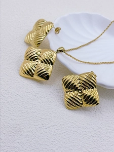 Detail view of gold necklace and earrings with diamond quilted texture on white shell
