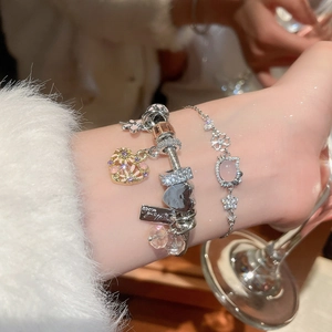 Detailed view of layered silver bracelets featuring a pink cat charm and heart pendants