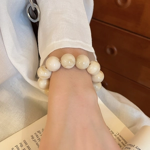 Close-up of cream marble texture acrylic beaded bracelet on a vintage book