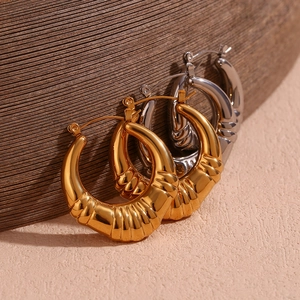 Detailed view of chunky ribbed hoop earrings in polished gold and silver metallic finish