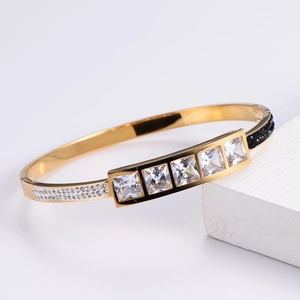 Detail of gold-plated bangle with five square zircons and black-white side crystals