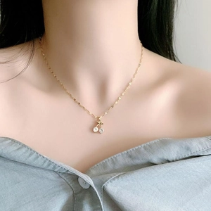 Elegant gold cherry pendant necklace with crystals on fine chain worn by a model