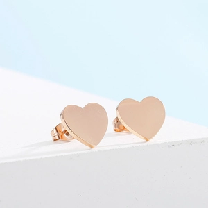 Vue détaillée des boucles d'oreilles cœur dorées polies sur un support minimaliste