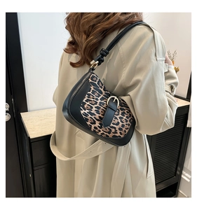 Detailed view of leopard print shoulder bag with gold buckle on a beige coat outfit