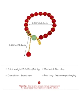 Détail d'un bracelet en perles rouges avec papillon en émail et pendentif doré Ping-An