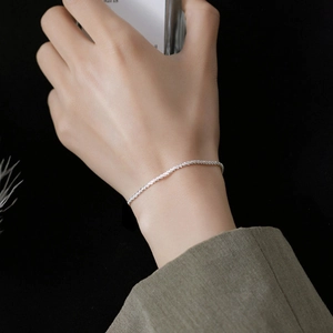 Detailed close-up of a shimmering 925 silver chain worn on a wrist against black background