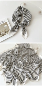 Detail of a 70cm black and white striped silk scarf tied in a knot on a minimal background