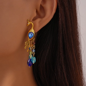Detail of vintage golden peacock earrings with colorful beaded tassels on model