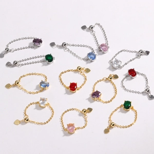 Macro shot of colorful oval zircon stone chain rings with heart charms in gold and silver