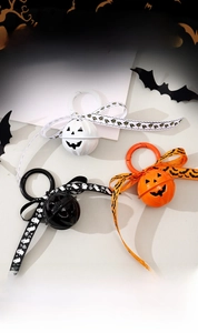 Detail of Halloween pumpkin metal bells with festive printed ribbons and plastic hooks