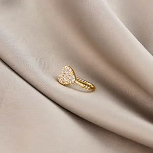 Close-up of golden heart-shaped non-piercing nose clip with micro-pave crystals on silk