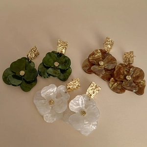 Three pairs of floral acrylic earrings in green, tortoiseshell, and white with gold accents