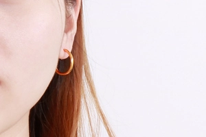 Close-up of gold 304 stainless steel hoop earring worn on a model's ear lobe