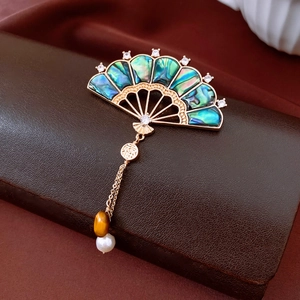 Detail of vintage fan brooch with gold plating, abalone shell, and dangling pearl tassel